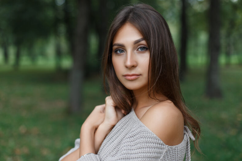 beautiful young fresh girl model in a fashion sweater in the park on green nature background