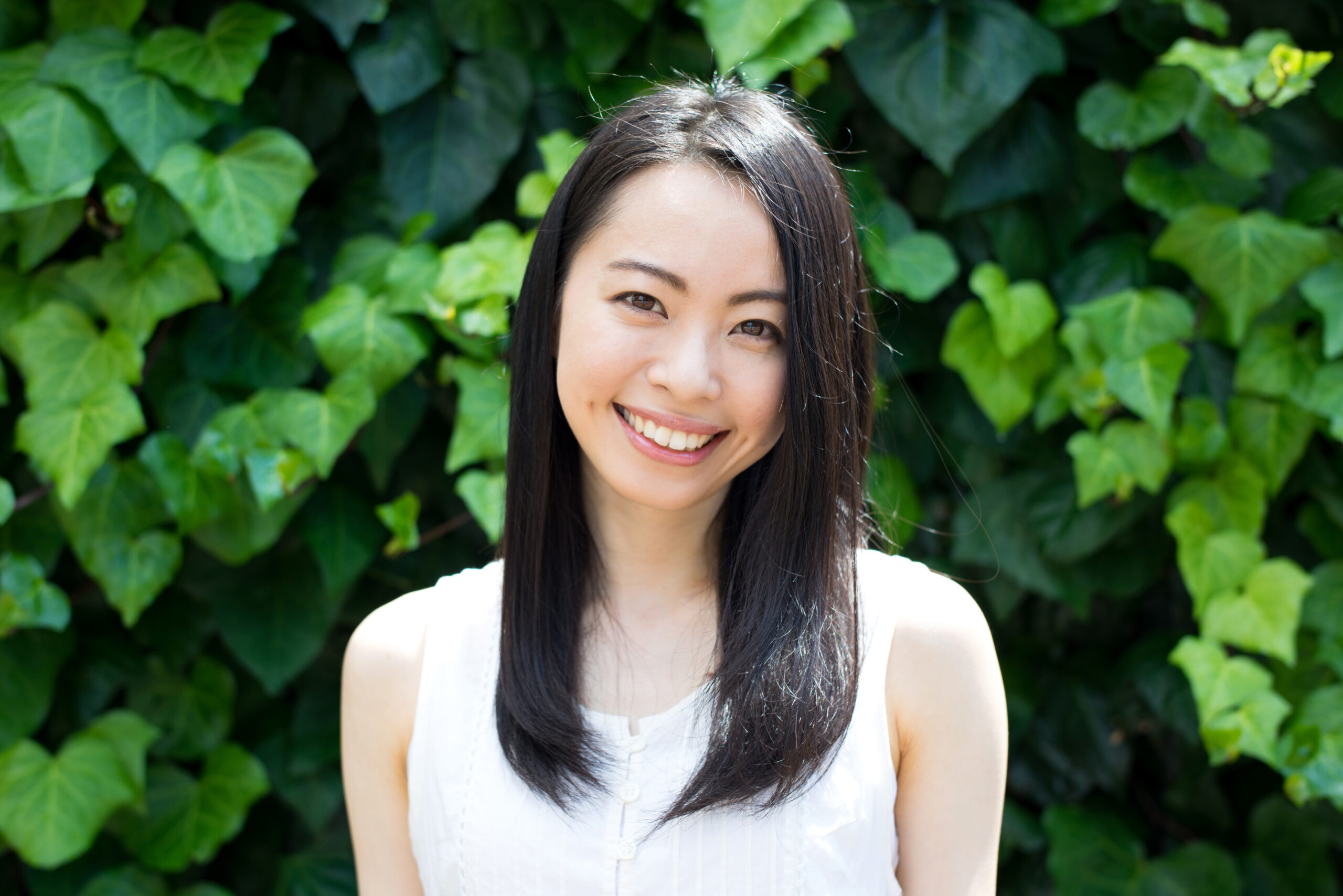 pretty asian woman smiling in front of ivy