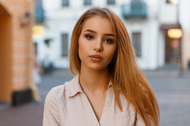 Stylish beautiful young blonde model girl in fashionable summer clothes walks in the city
