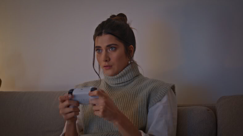 Serious girl gaming controller at night home closeup. Young focused woman holding joystick playing car racing games alone at evening living room. Involved millennial player enjoying console video game