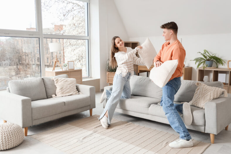 Young couple fighting pillows at home
