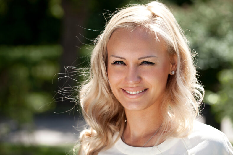 Closeup portrait of a young beautiful blonde girl in a summer park