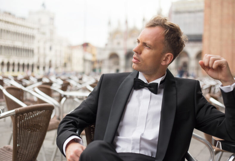 Stylish young man sitting in cafe in tuxedo