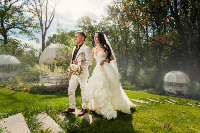 Beauty young couple of bride and groom in wedding suits in the park