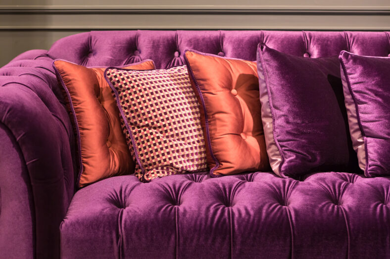 Close up of violet velvet sofa and cushions with vintage style.