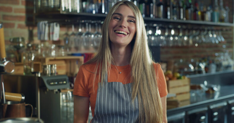 portrait of young friendly female bartender working at a bar during day time
