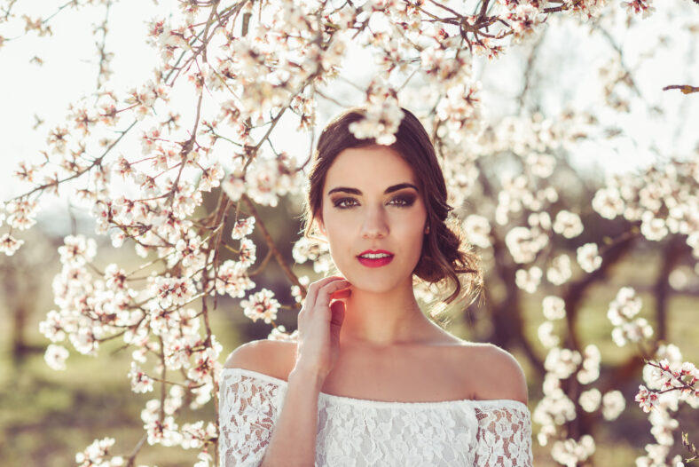 Portrait of young woman in the flowered garden in the spring time. Almond flowers blossoms