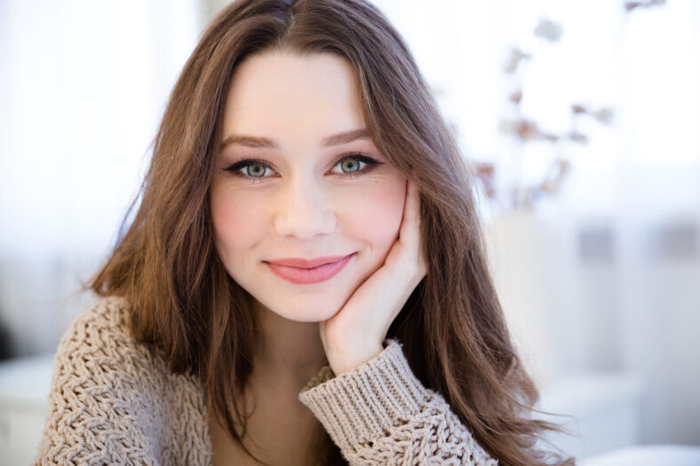 Portrait of beautiful happy young woman with long hair in the room