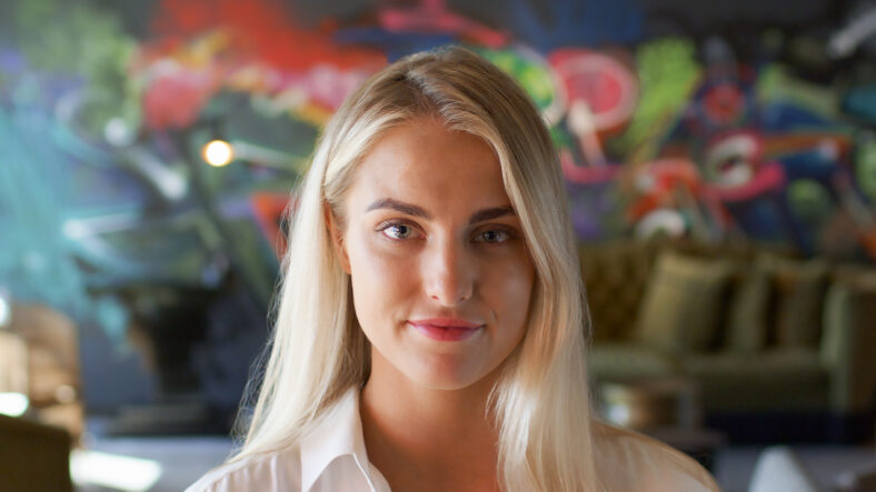Portrait Of Young Woman In Urban Setting With Graffiti Covered Wall Behind
