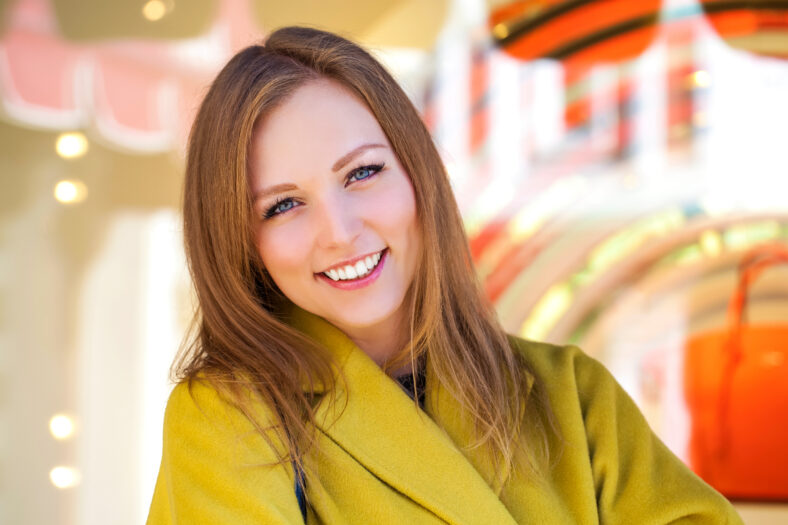 Portrait close up of young beautiful blonde woman, on spring street background
