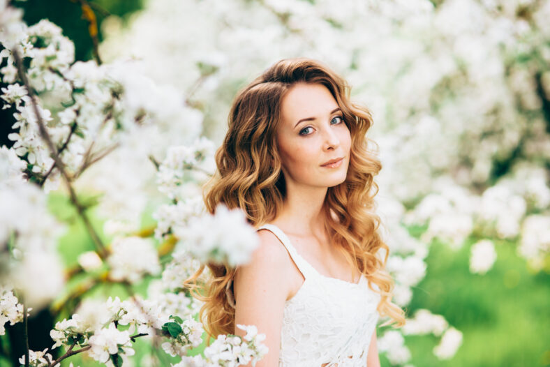 Spring beautiful romantic girl, blonde, standing in a blooming Apple orchard .