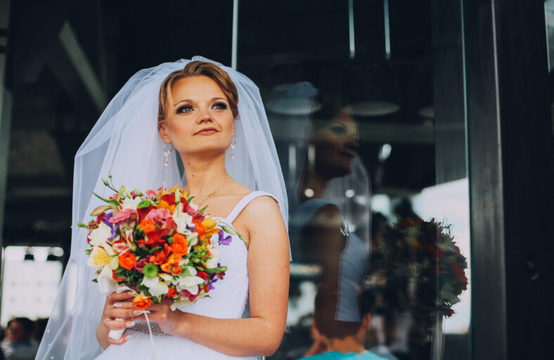portrait of happy bride with a bouquet in hands. near the glass modern building
