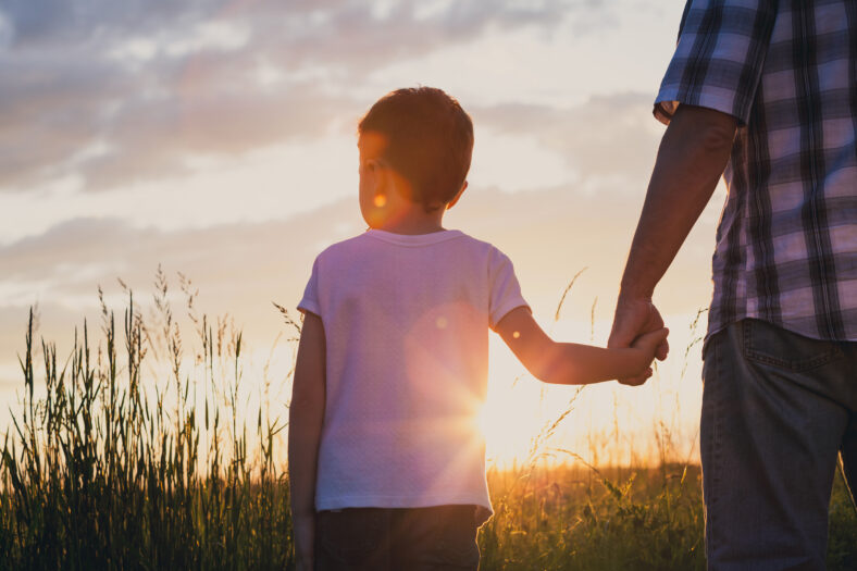 Father and son playing at the park at the sunset time. Concept of friendly family.