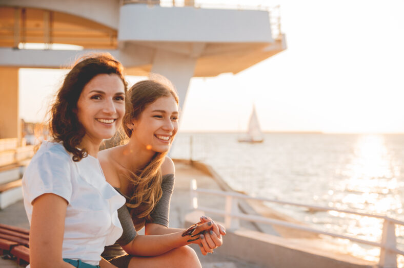 Close-up portrait of happy mother with a teenage daughter. Sunset light.