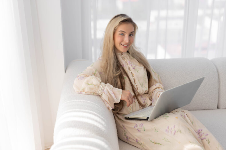 beautiful young happy woman with laptop on sofa