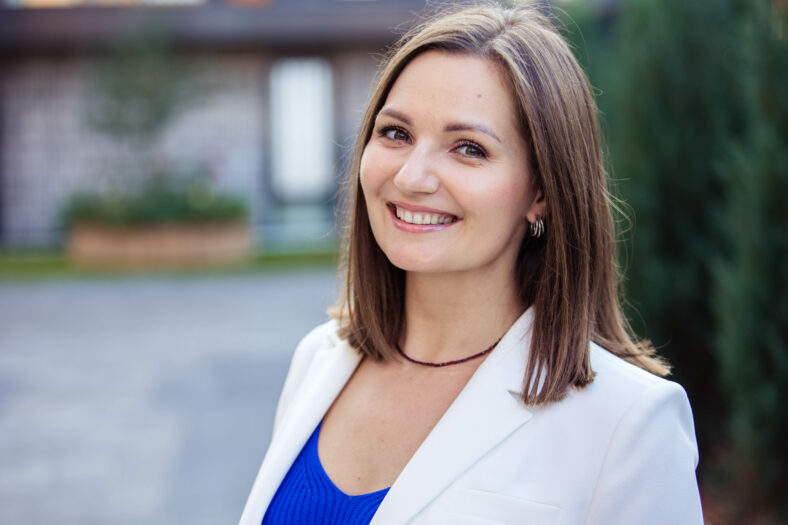 Portrait of a young happy woman in the background of a modern city, looking at the camera, smiling. Close up.