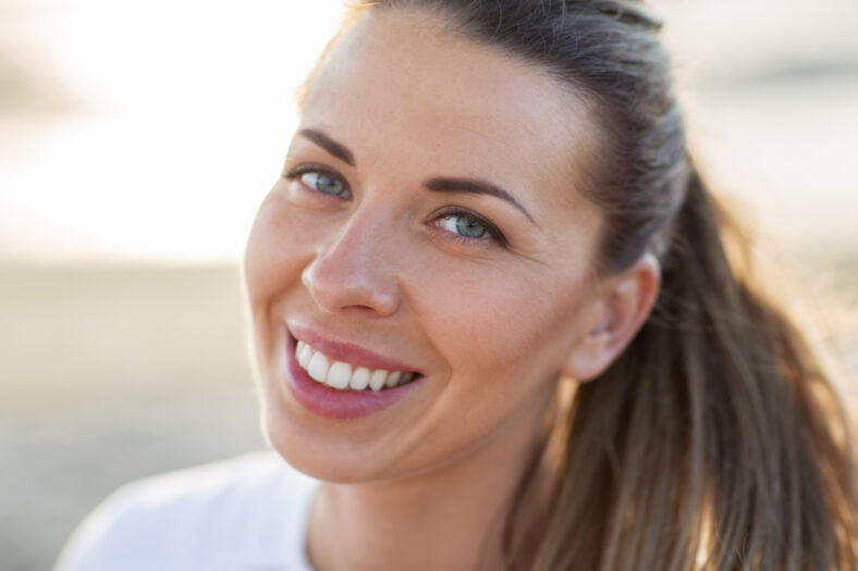 people, emotion and facial expression concept - close up of happy smiling young woman face outdoors