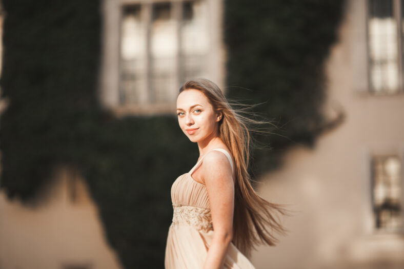 Beautiful girl with long hair posing in old castle with columns. Krakow Vavel.