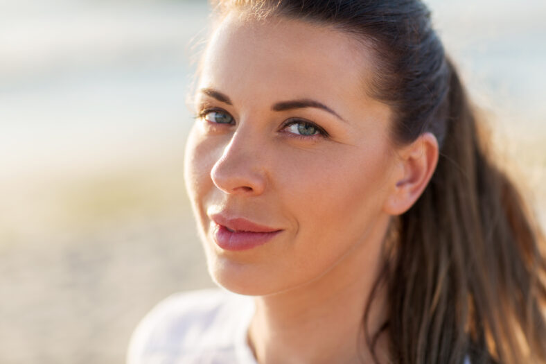 people, facial expression and emotion concept - close up of happy young woman face