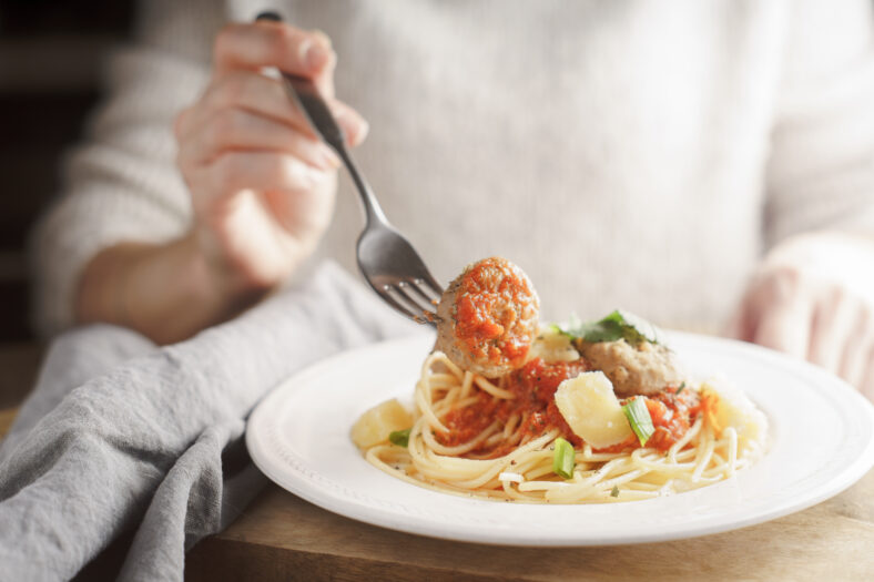 Woman eating spaghetti with meatballs