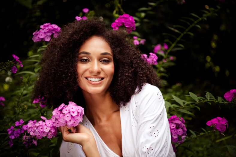 Photo of adorable cheerful girl dressed white stylish clothes enjoy blooming fresh flowers in botanical garden outdoors.