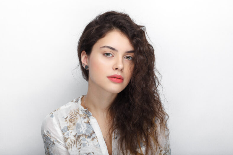 Beauty portrait of young adorable fresh looking brunette woman with long brown healthy curly hair. Emotion and facial expression lifestyle concept.