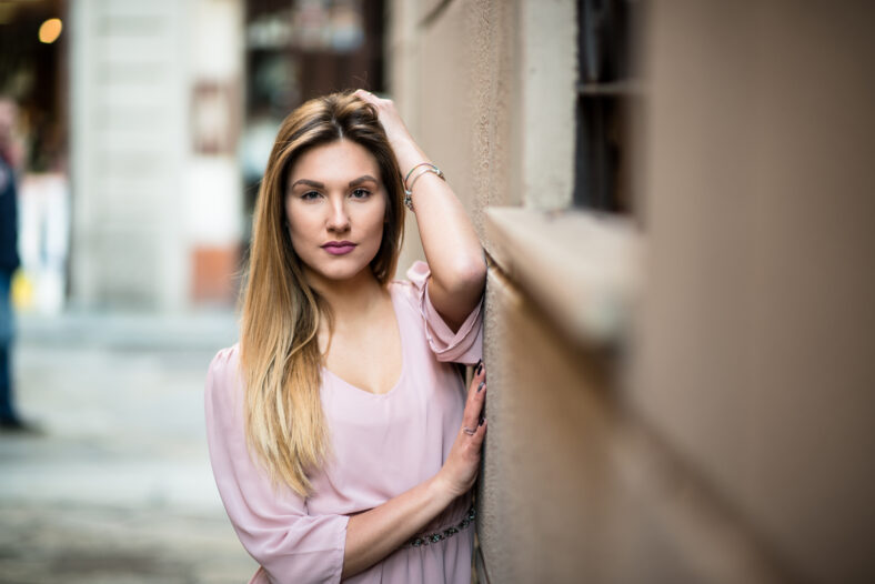 Mujer rubia bastante inclinada contra un edificio