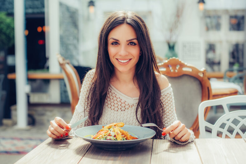 Young woman enjoying food in a restaurant, having her lunch break. Close up