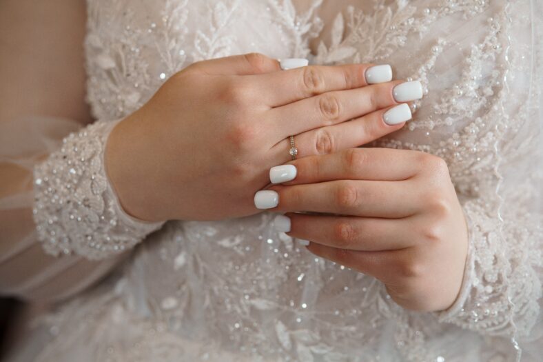 Close-up shot of a bride's hands displaying a delicate diamond engagement ring, symbolizing love, commitment and a joyous wedding moment