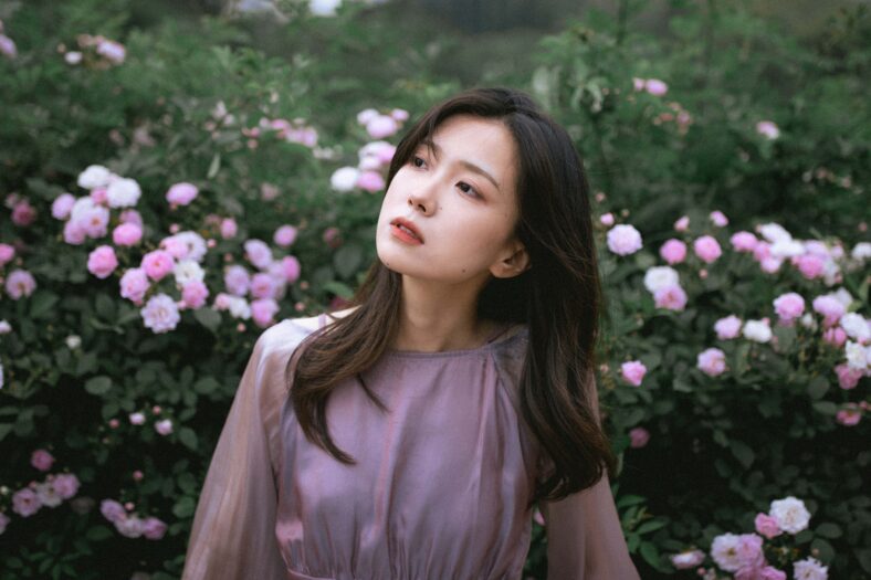 Young Asian woman among blooming pink flowers.
