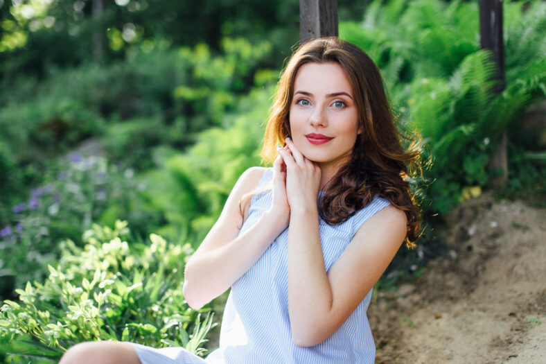 Girl pose to camera at park background with her dress