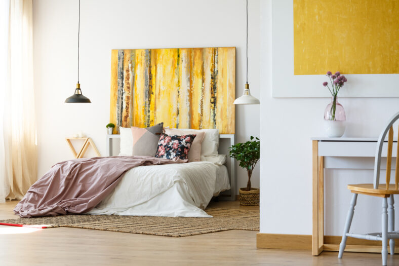Energetic and warm bedroom with yellow artwork, plant and desk