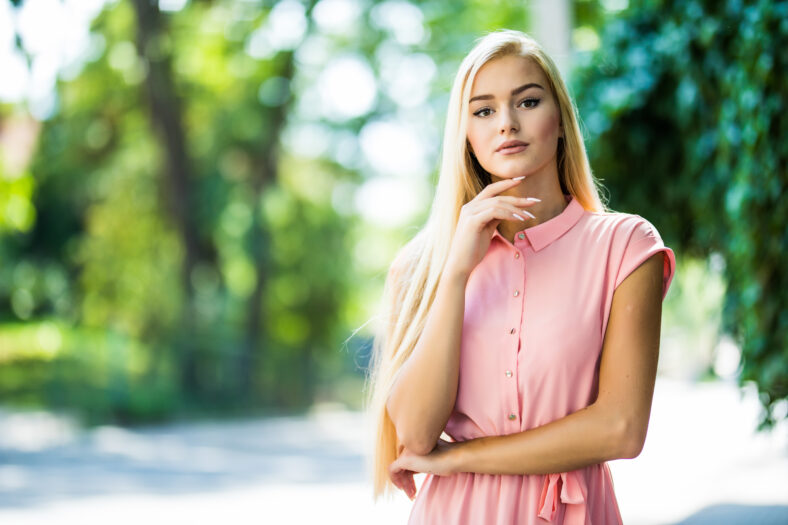 Blonde woman in green leaves enjoying nature.