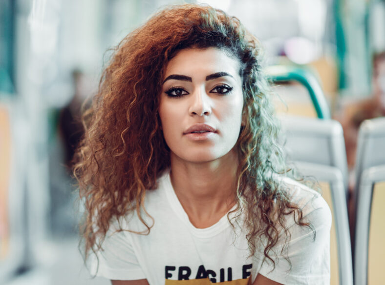 Arabic woman sitting inside subway train. Arab girl in casual clothes near a window.