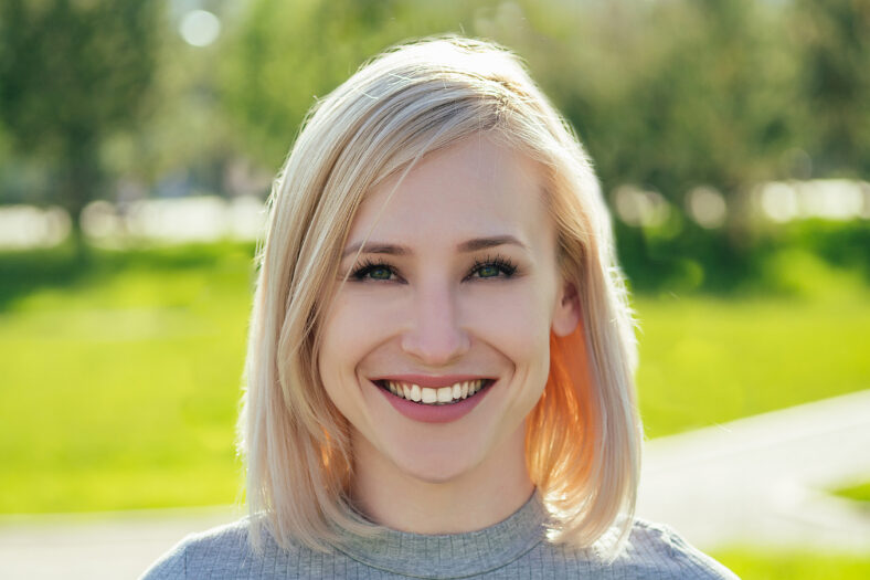 attractive blonde woman in the park on a background of green grass