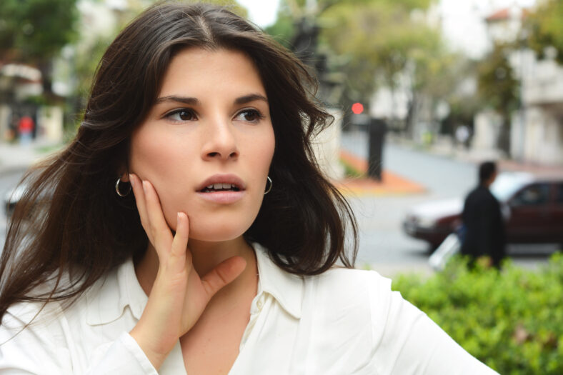 Close up portrait of a beautiful young woman with surprised expression. Unbelieving, outdoor.