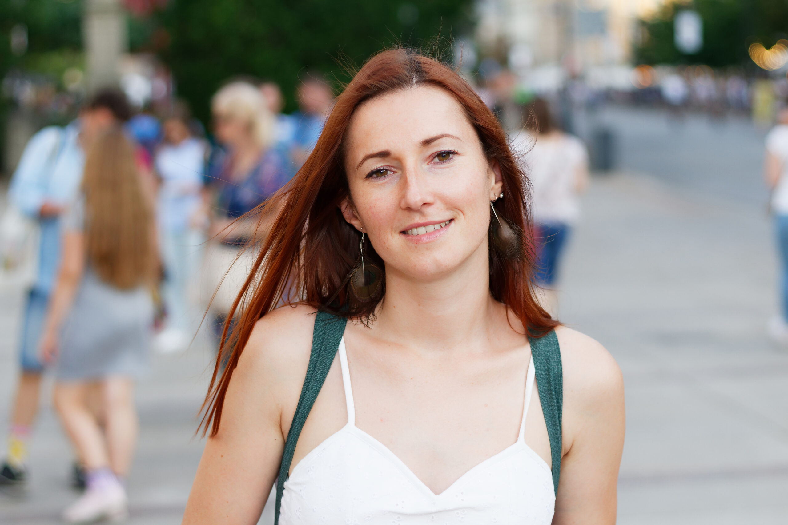 Mujer sonriente bastante joven yendo por una calle