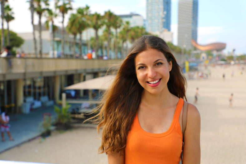 Attractive smiling city woman enjoying her leisure time in Barceloneta beach, Barcelona, Spain