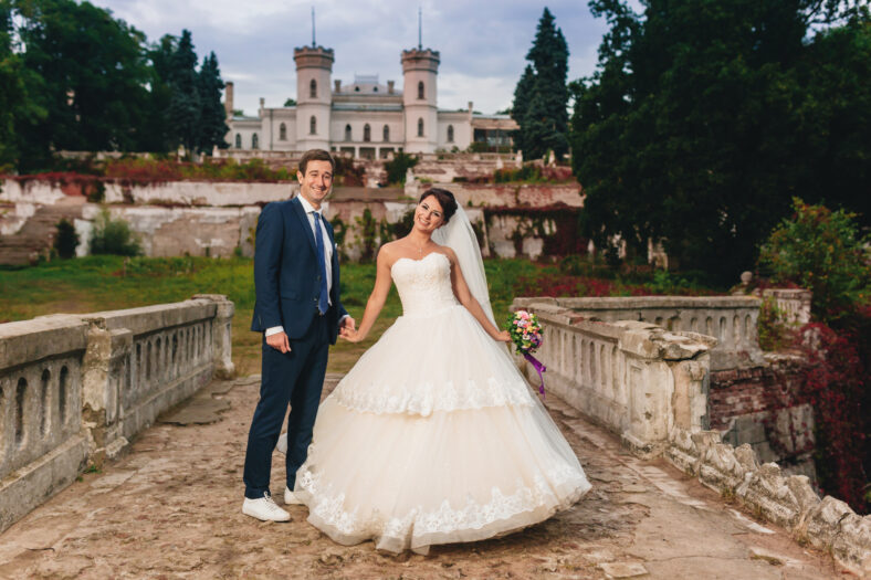 The bride and groom walking along the old bridge. At background the old castle