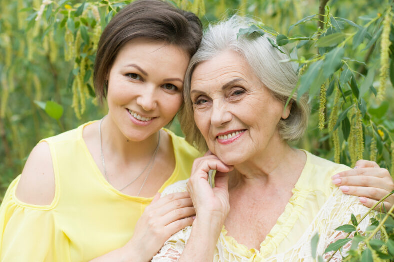 Happy senior mother and adult daughter posing together outdoors