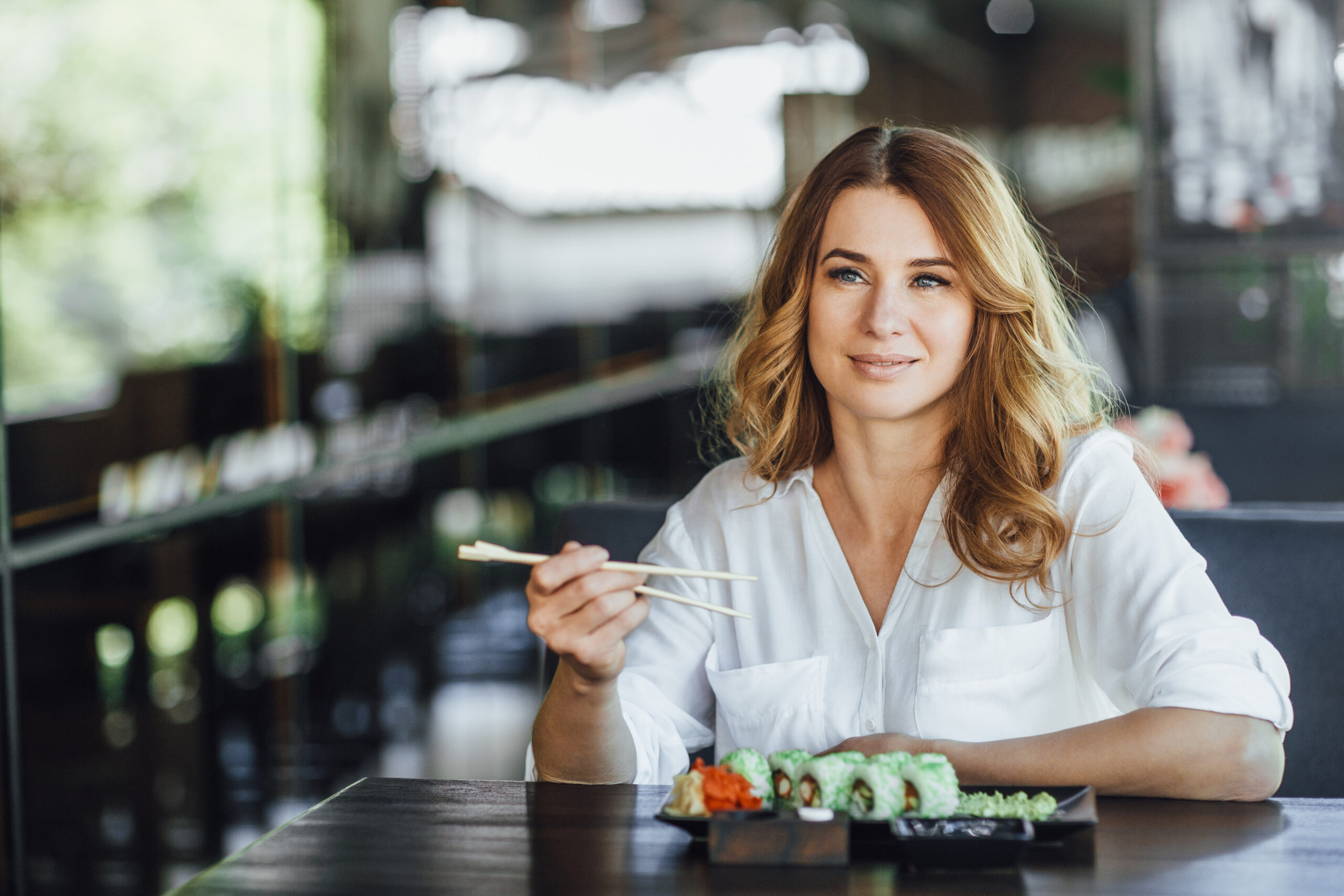 A beautiful blond middle-aged woman dining with California's role in a Japanese restaurant on the summer terrace.