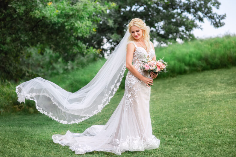 beautiful bride in wedding dress with long veil fluttering in the wind outdoors