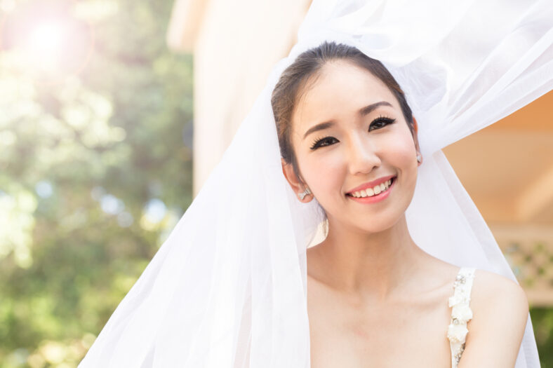 Hermosa novia asiática atractiva mujer con vestido de novia y sosteniendo una sonrisa de ramo y felicidad en el día de la boda