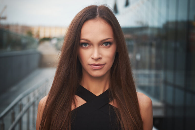 Beautiful woman face. Cute girl with long hair on the street in the city