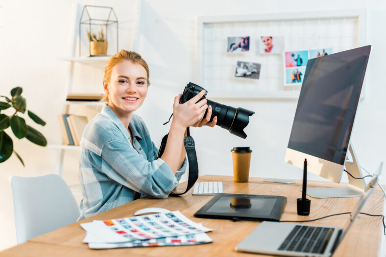 beautiful young female photographer smiling at camera while working in office