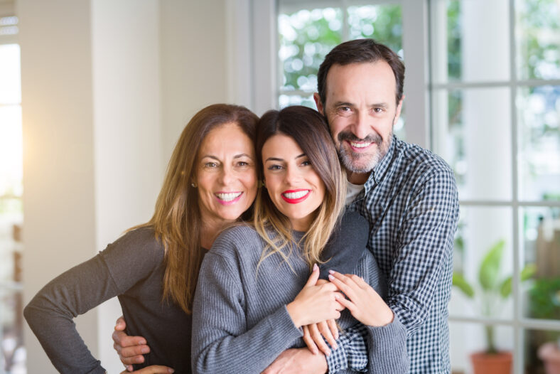 Beautiful family together. Mother, father and daughter smiling and hugging with love at home.