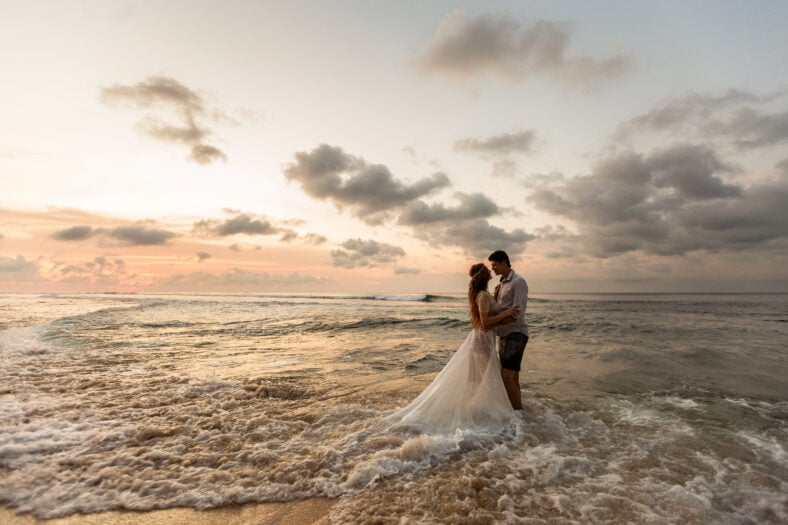 Bride and groom hugging on the beach standing in the sea water