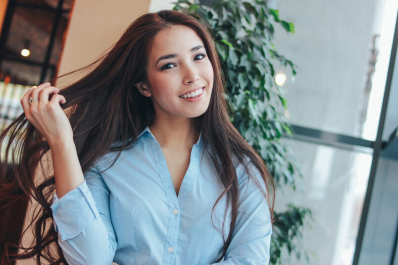 Portrait of beautiful charming romantic brunette long hair smiling asian girl near the window at cafe