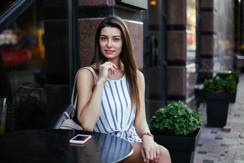 Young pretty woman blogger in cafe with smartphone