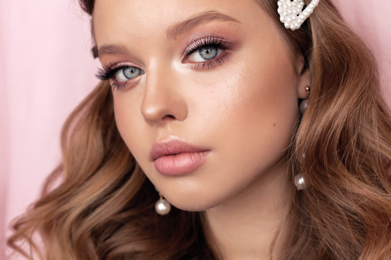 fashion photo of beautiful young woman with dark natural hair and tender makeup with pearl accessories